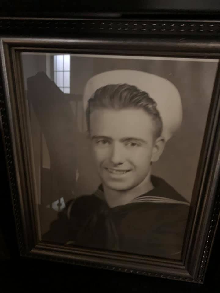 Man in navy uniform in a black and white framed portrait